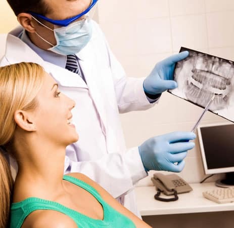 Dentist showing dental X-rays to female patient in clinical office setting.