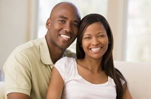 Happy couple smiling together indoors in bright, modern setting for dental practice website.