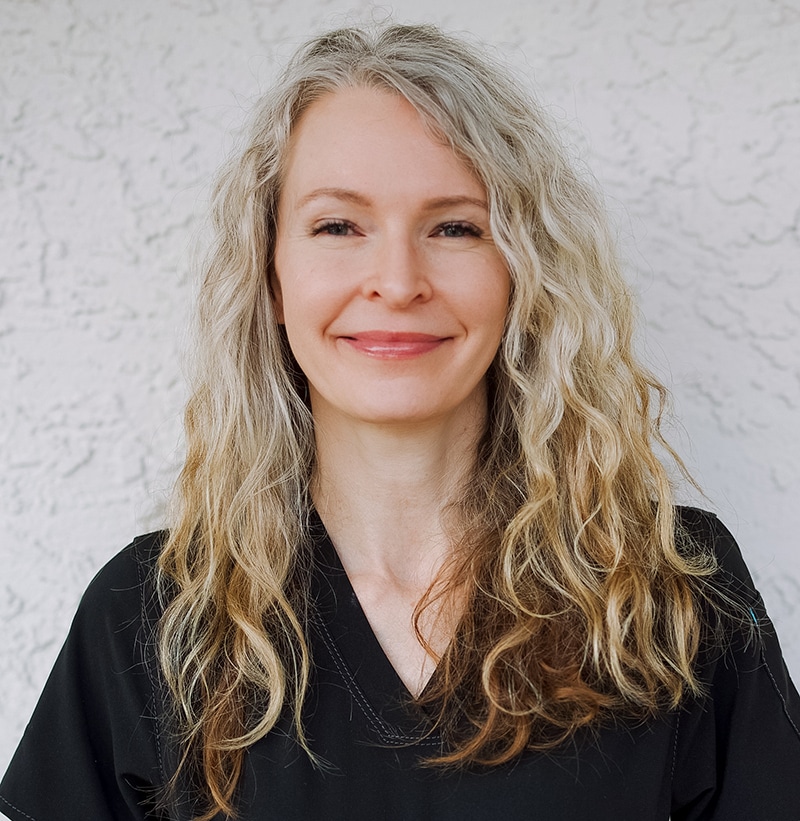Professional headshot of woman with long wavy blonde hair smiling at camera against white background.