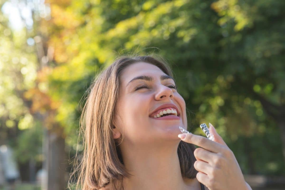 Young adult smiling while holding Invisalign case.